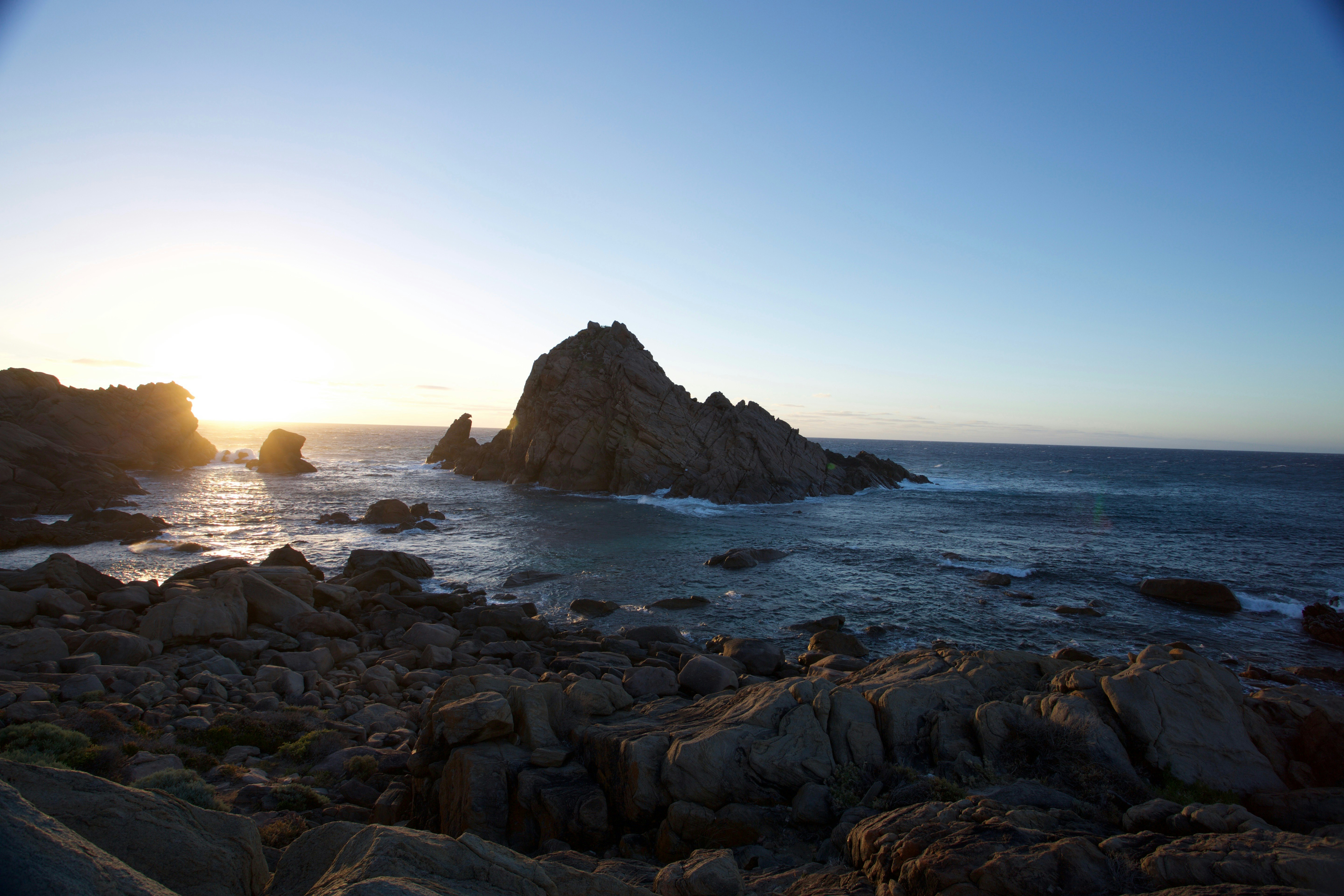 aerial photography of rock islet near sea shore